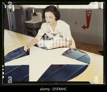 Peindre l'insigne américain sur les ailes d'un avion est un travail que Mme Irma Lee McElroy, une ancienne employée de bureau, fait avec précision et zèle patriotique. Mme McElroy est une employée de la fonction publique à la base navale aérienne de Corpus Christi, Texas. Son mari est un f Banque D'Images