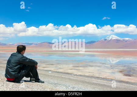 Homme assis seul sur la rive de la Laguna Colorada, Bolivie Banque D'Images