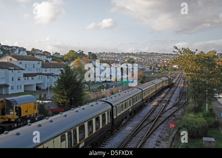 Train à vapeur et voitures traversant Paignton Banque D'Images