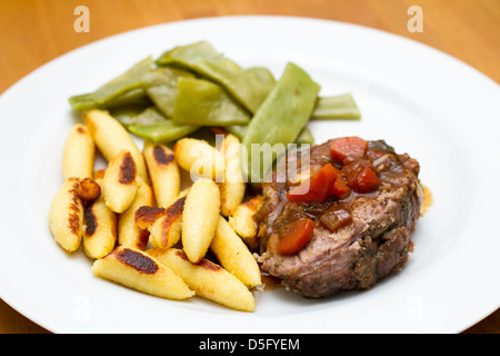 Gigot d'agneau en forme de doigt boulettes de pommes de terre et haricots de printemps Banque D'Images