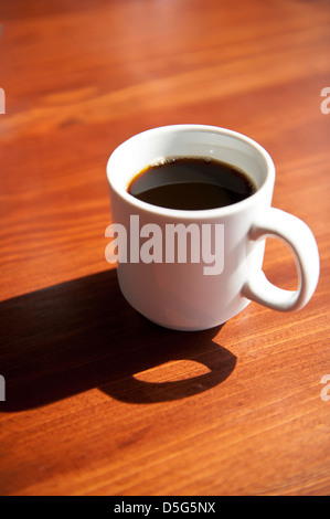 Tasse de café fumant dans une tasse blanche sur une table en bois Banque D'Images