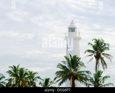 Phare blanc au-dessus de hauts palmiers sur fond de ciel nuageux, Galle Sri Lanka Banque D'Images