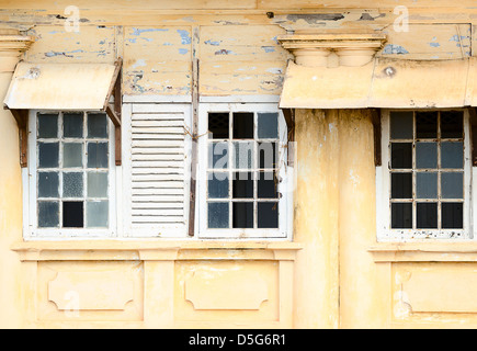 Grunge ramshackle fenêtres avec du verre brisé sur le mur jaune Banque D'Images