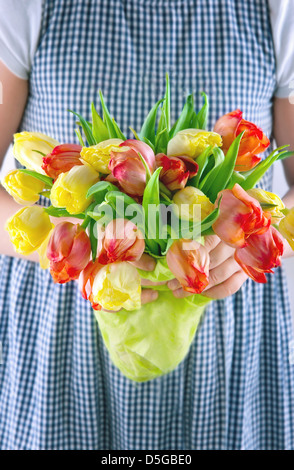 Petite fille dans une robe d'été de remettre un bouquet de tulipes jaunes et orange Banque D'Images