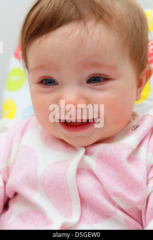 Huit mois baby girl wearing barboteuse rose représentée dans sa chaise haute sur sa première fête de Pâques. Banque D'Images