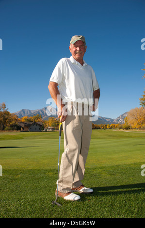 Un homme Senior citizen est heureux avec son jeu de golf sur un parcours de golf de montagne. Banque D'Images