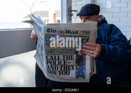 Un homme dans un chapeau plat lit le Daily Mail dans un café Banque D'Images