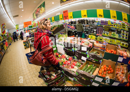 Une femme d'âge moyen pour les légumes frais de magasinage et d'autres produits alimentaires dans un supermarché discount LIDL, UK Banque D'Images