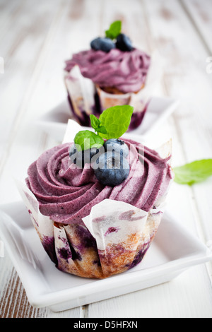 Blueberry cupcakes avec le glaçage, les bleuets et les feuilles de menthe Banque D'Images