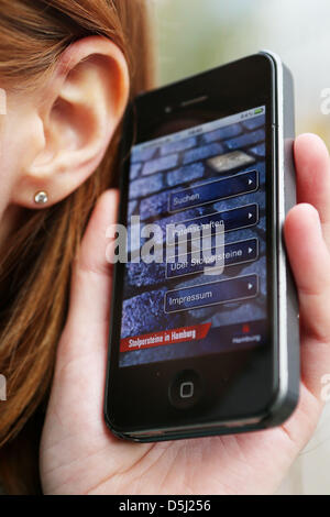 Un téléphone avec le 'Stumbling blocks à Hambourg' app est tenu à côté d'une oreille à Hambourg, Allemagne, 12 novembre 2012. L'achoppement des plaques commémoratives dans les trottoirs de rappeler la déportation des victimes de l'époque nazie. De plus à la mémoire des plaques et les applications existantes, deux étudiants ont maintenant créé des blocs audio d'achoppement. Acteurs et intervenants professionnels raconter les récits des victimes. Banque D'Images