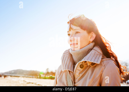 Jeune femme à l'extérieur dans le soleil d'hiver par la côte Banque D'Images