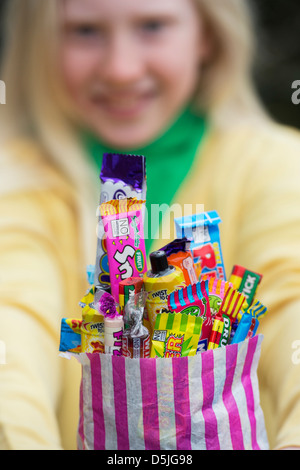 Girl holding un sac d'assortiment de bonbons et sucreries rétro pour enfants Banque D'Images