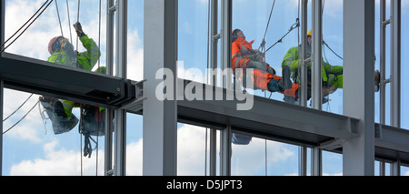 La pendaison des ouvriers sur des cordes sur la face externe d'un bâtiment en forme de tour de Londres d'effectuer des travaux de maintenance Banque D'Images