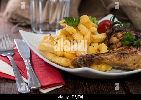 Cuisses de poulet grillées avec des frites sur une assiette Banque D'Images