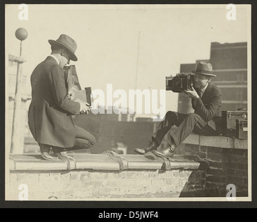 Une photographie de deux photographes, chacun utilisant des appareils photo portatifs pour se capturer l'un l'autre tandis qu'ils sont perchés sur un toit à Nice, en France. L’image illustre la pratique de la photographie de rue au début du XXe siècle. Banque D'Images