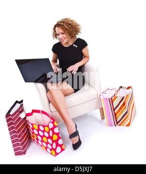 Belle jeune femme assise sur un fauteuil avec des sacs de couleur à partir d'Internet shopping Banque D'Images