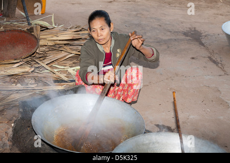 Femme en remuant le sucre de palme bouillante, Kyaukpadaung, près de Bagan, Myanmar (Birmanie), Banque D'Images