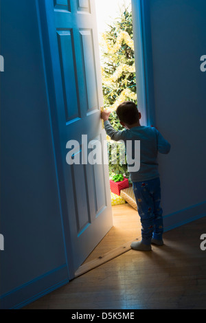 Boy (4-5) peeking through doorway Banque D'Images