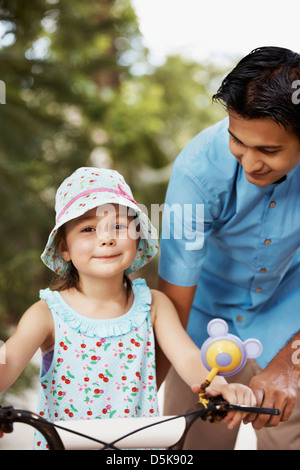 Aider l'homme girl (6-7) riding bicycle Banque D'Images