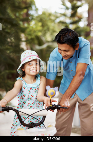 Aider l'homme girl (6-7) riding bicycle Banque D'Images