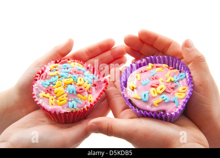 Deux petites mains décorées avec des gâteaux de tasse sur fond blanc Banque D'Images