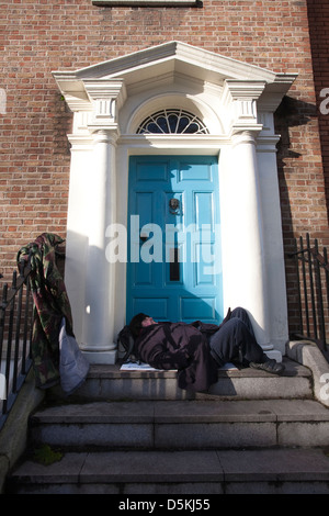 Sans-abri dormir sur une porte en face des bâtiments du gouvernement irlandais sur Kildare Street Dublin en Irlande. Banque D'Images