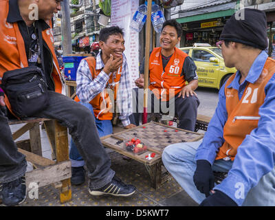 Le 4 avril 2013 - Bangkok, Thaïlande - les chauffeurs de taxi moto jouer aux dames pendant l'attente pour les clients à la station de taxis à Bangkok. L'expansion économique de la Thaïlande depuis les années 1970 a considérablement réduit la quantité de la pauvreté et la sévérité de la pauvreté en Thaïlande. Dans le même temps, l'écart entre les très riches en Thaïlande et les très pauvres est devenue telle que la disparité des revenus est plus importante maintenant que c'était en 1970. Les scores de la Thaïlande sur le .42 ''Ginni Index'' qui mesure la disparité des revenus sur une échelle de 0 (parfait l'égalité des revenus) à 1 (inégalité absolue dans laquelle une personne est propriétaire de tout). Banque D'Images