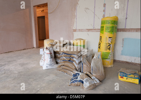 Sacs de ciment plâtre isolants rockwool entassés à l'intérieur d'une chambre nouvellement plâtrés et entrée au plancher de béton couloir Banque D'Images