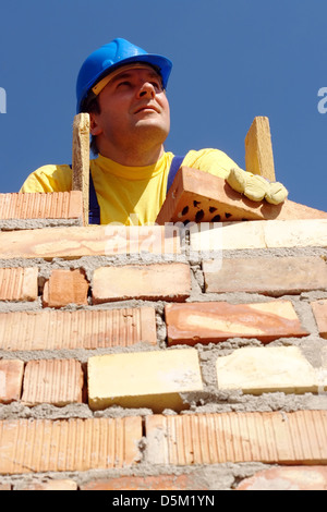 Avec des briques du mur du bâtiment Mason sur l'échelle en bois debout Banque D'Images