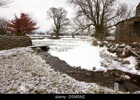 Petit ruisseau qui traverse le village Carperby en hiver neige au sol du Yorkshire, Royaume-Uni, Angleterre Banque D'Images