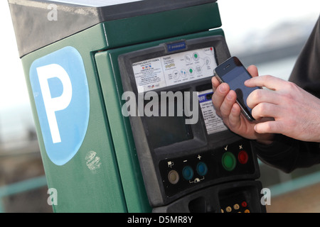 Un homme photographié en utilisant son téléphone mobile pour payer un ticket de parking à un billet sur Maderia dur à Brighton, East Sussex, Banque D'Images