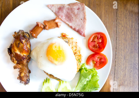 Un plat de riz frit avec du poulet frit, jambon, saucisses et œufs. Banque D'Images