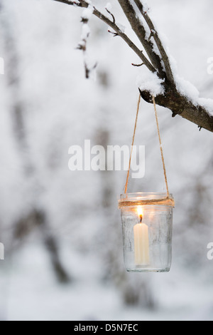 Bougie de Noël dans un bocal en verre dans un bois couvert de neige Banque D'Images