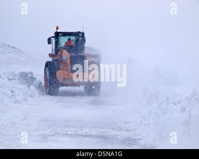 Un tracteur / digger essayant de garder un Peak District route ouverte dans l'accumulation de neige durant l'hiver de 2013 Banque D'Images