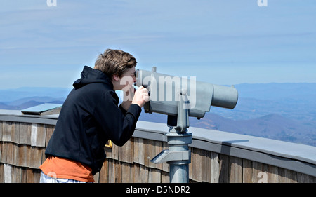 Un jeune garçon sur Brasstown Bald regardant la vue avec un télescope. Banque D'Images