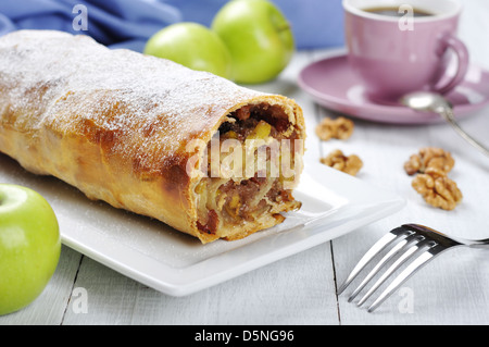 Strudel aux pommes sur un plat avec les pommes fraîches et tasse de café Banque D'Images