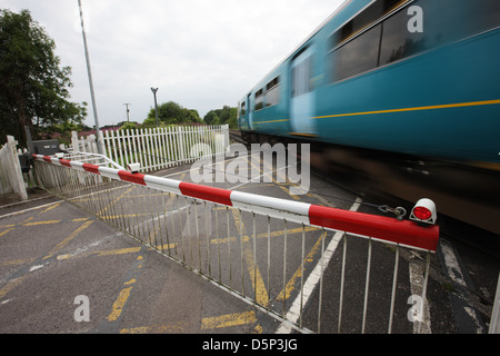 Le passage à niveau automatique mais sans pilote du chemin de fer rural est fermé à la circulation alors qu'un Arriva fonctionnait à des vitesses de train à travers la jonction, Gloucestershire. Banque D'Images