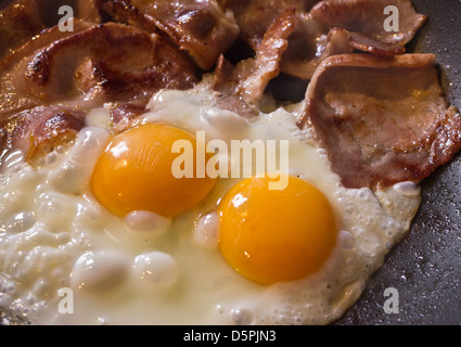 Oeufs et bacon vitellus double pour le petit-déjeuner de cuisson Banque D'Images