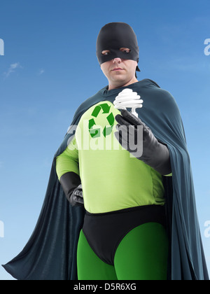 Avec super-héros Eco recyclage vert symbole de flèche sur la poitrine tenant lfc debout au-dessus de ciel bleu - concept d'économie d'énergie Banque D'Images