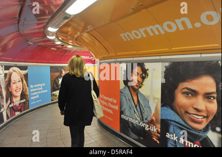 La station Oxford Circus, Londres, Royaume-Uni. 8 avril 2013. Les navetteurs et les touristes passent par les affiches dans le métro pour l'église des Mormons. L'Église de Jésus-Christ des Saints des Derniers Jours lance une campagne de publicité à Londres avec les mots 'Je suis un Mormon" et "Demander à un mormon', la campagne en stations de métro et sur les bus est à l'arrière de la scène de la comédie musicale, Le Livre de Mormon. Banque D'Images