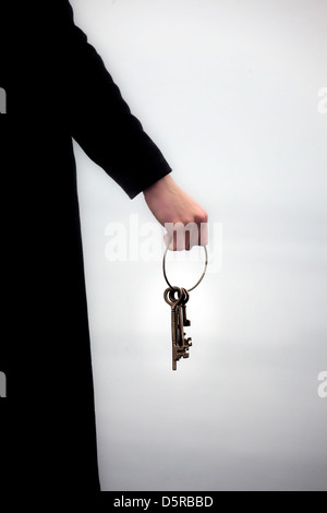 Un homme en habit noir tenant un porte-clés avec des anciennes clés Banque D'Images