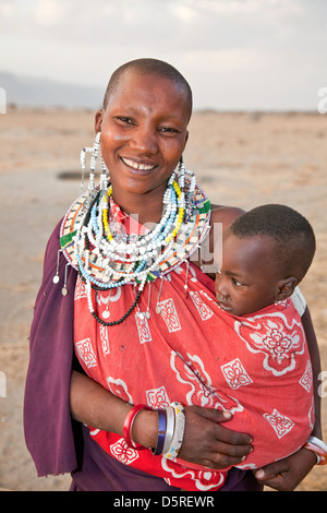 L'Afrique, Tanzanie;Maasai smiling woman ou la mère avec deux bébés dans ses bras en costume traditionnel avec des bijoux faits main Banque D'Images