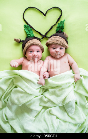 Deux frères jumeaux bébés portée au acorn hats Banque D'Images