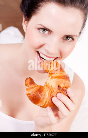 Smiling woman portrait de manger un croissant pour le petit déjeuner Banque D'Images