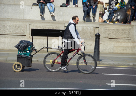 L'homme sur un vélo tirant une remorque dans le centre de Londres (Trafalgar Square). Banque D'Images
