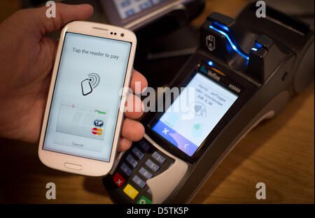 Un smartphone NFC (Near Field Communication) qui est équipé de la Telekom app monportefeuille est tenir en face d'un terminal de paiement à la tendance de Bitkom congrès à Berlin, Allemagne, 27 novembre 2012. Téléphone mobile NFC peut être utilisé pour les paiements en touchant simplement le téléphone sur n'importe quel terminal compatible PayPass à commander. L'Association fédérale pour la technologie de l'information, Télécom Banque D'Images