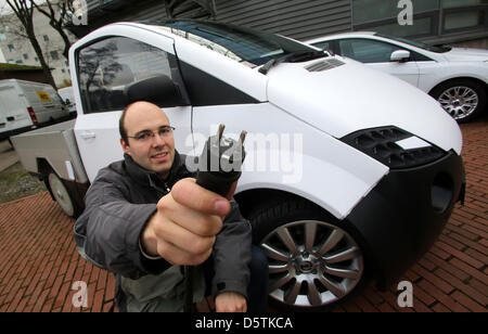 Den Stromstecker für das 'Elektrokleintransporter BOmobil', ein, hält am 27.11.2012 à Essen (Nordrhein-Westfalen) ein Student der Universität Bochum auf einem Kompetenztreffen vor das Auto. Thema des Treffens ist die Elektromobilität en Nordrhein-Westfalen. Photo:Roland Weihrauch/dpa Banque D'Images