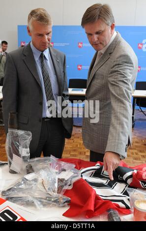 La Basse-saxe Ministre de l'intérieur, Uwe Schuenemann (R) et de la Police d'Hanovre le président Axel Brockmann (L) se tenir en face de NPD des pancartes, ont saisi des armes et du matériel de propagande après une conférence de presse au Ministère de l'Intérieur à Hanovre, Allemagne, 25 septembre 2012. La Basse-Saxe a interdit le plus important groupe néo-nazi dans l'État allemand. Depuis 2008, le groupe avait procédé à Banque D'Images