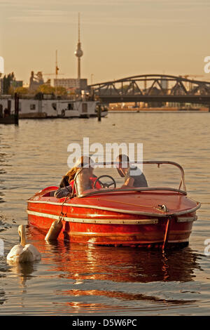 Un homme et une femme de nourrir une swan pendant le coucher du soleil alors qu'ils sont assis dans un bateau sur la rivière Spree à Berlin, Allemagne, 02 octobre 2012. Photo : Robert Schlesinger Banque D'Images