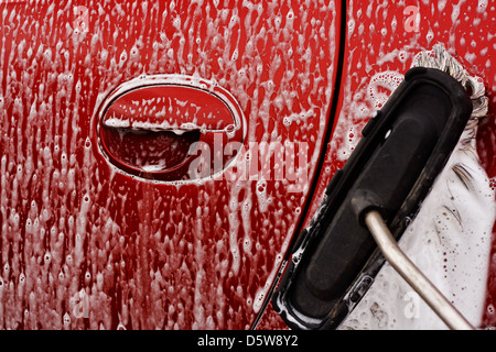 Laver la voiture avec savonneux brosse douce à un lavage de voiture Banque D'Images